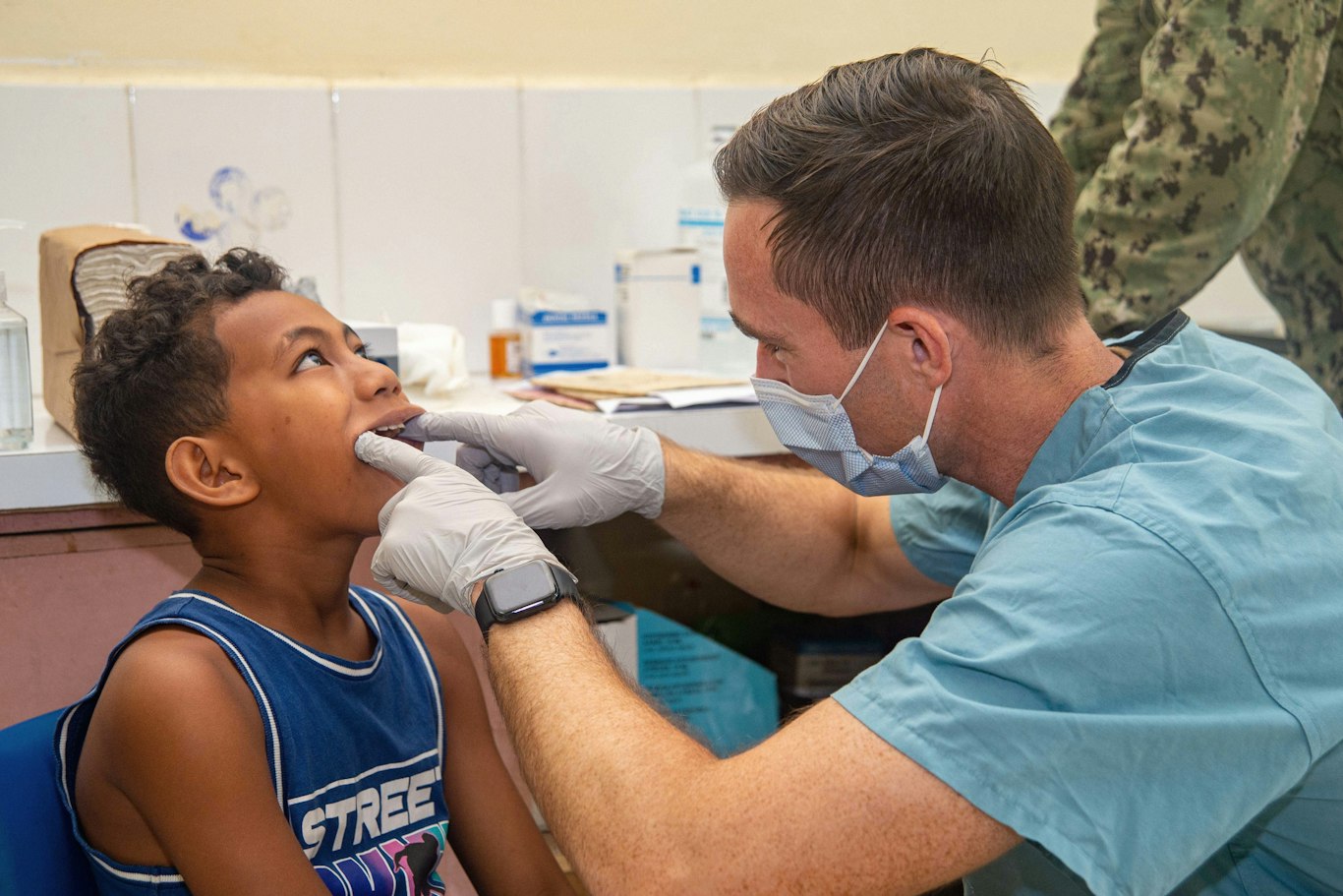 Dentist examining a young boy's teeth during a child's first dental visit